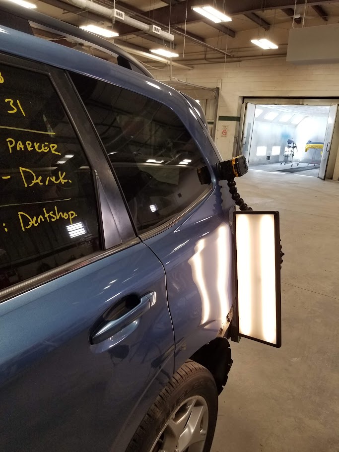 Blue SUV rear quarter panel dent under PDR light board before repair