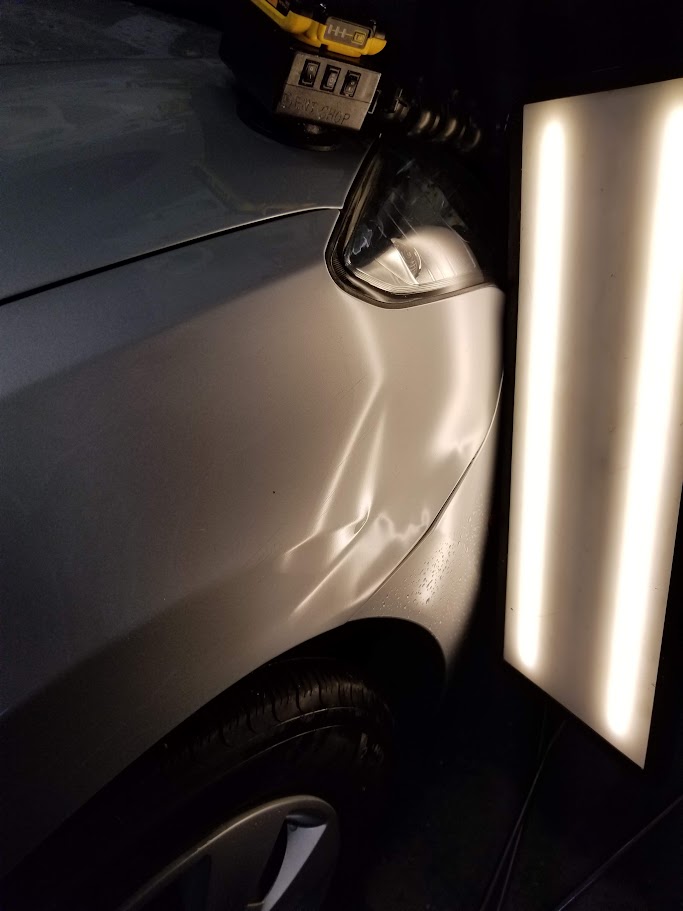 Fender panel inspected under PDR light after repair